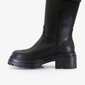 Bota Syra negra Sofia Sarkany, caña media con hebilla lateral y cierre. Suela track y taco robusto, para looks urbanos.