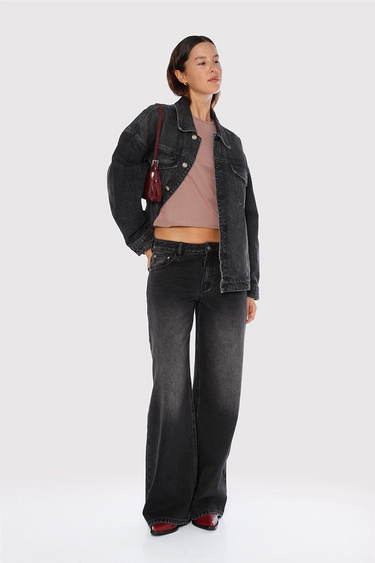 Modelo con Jean Kip Sofia Sarkany negro wide leg lavado, campera denim y top corto. Ideal para un look urbano.