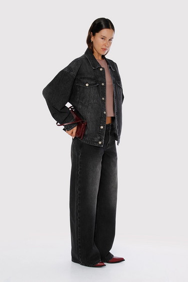 Modelo con Jean Kip Sofia Sarkany negro gastado, tiro alto y pierna ancha. Camperón denim a juego.