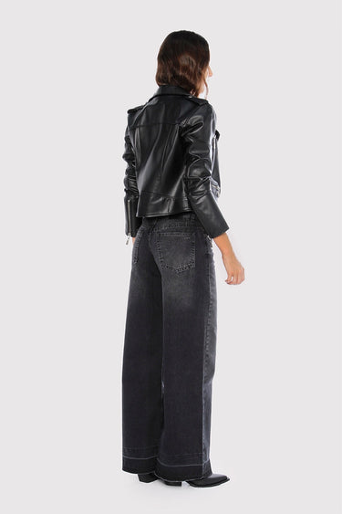 Modelo de espaldas luciendo una campera de cuero negra Sofia Sarkany Pra con jeans amplios, un look canchero y urbano.