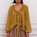Blusa Klen mostaza Sofia Sarkany, escote V con volados, lazo y mangas largas. Look canchero y moderno.