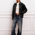 Sofia Sarkany Campera Rume negra bomber de cuero, con cuello y cierres, en un look canchero con jeans de mujer. Moda urbana.