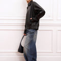 Modelo luciendo la Campera Rume negra de Sofia Sarkany, combinada con jeans anchos, gorra y cartera. Un look canchero.