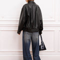 Campera Rume negra Sofia Sarkany, espalda de cuero oversize. Look urbano canchero con jeans anchos y gorra.