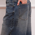 Detalle del Jean Strap Sofia Sarkany, denim azul con tiras decorativas laterales y mano en bolsillo. ¡Un toque distinto para vos!