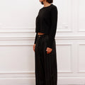 Mujer luciendo Sweater Bonn negro cropped Sofia Sarkany, con pantalón rayado. Look casual y moderno.