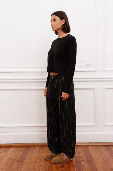 Mujer luciendo Sweater Bonn negro cropped Sofia Sarkany, con pantalón rayado. Look casual y moderno.