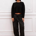 Mujer luciendo Sweater Bonn Sofia Sarkany negro cropped con pantalón rayado, estilo casual urbano.