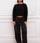 Mujer luciendo Sweater Bonn Sofia Sarkany negro cropped con pantalón rayado, estilo casual urbano.