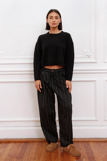 Mujer luciendo Sweater Bonn Sofia Sarkany negro cropped con pantalón rayado, estilo casual urbano.